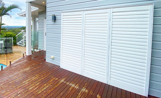 White External Shutters Frame A Deck With A Sparkling Pool — Premium Window Coverings In Chevallum, QLD